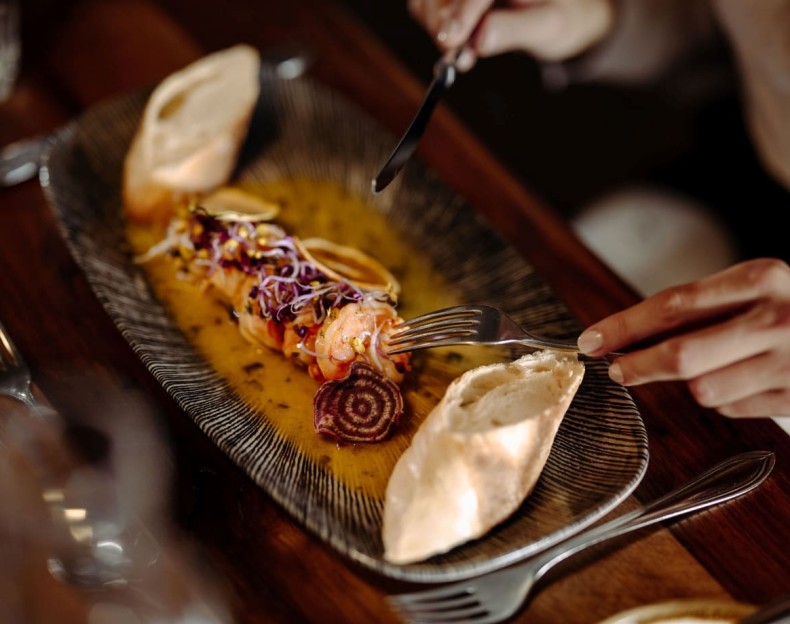 Gourmetgericht mit Garnelen, Gemüsegarnitur und Brot serviert